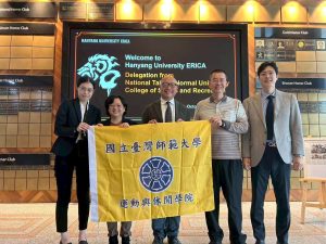 休旅所代表團與漢陽大學運動科學部Park Jae-Woo主任於漢陽大學安山校區主大樓歡迎海報前合影。